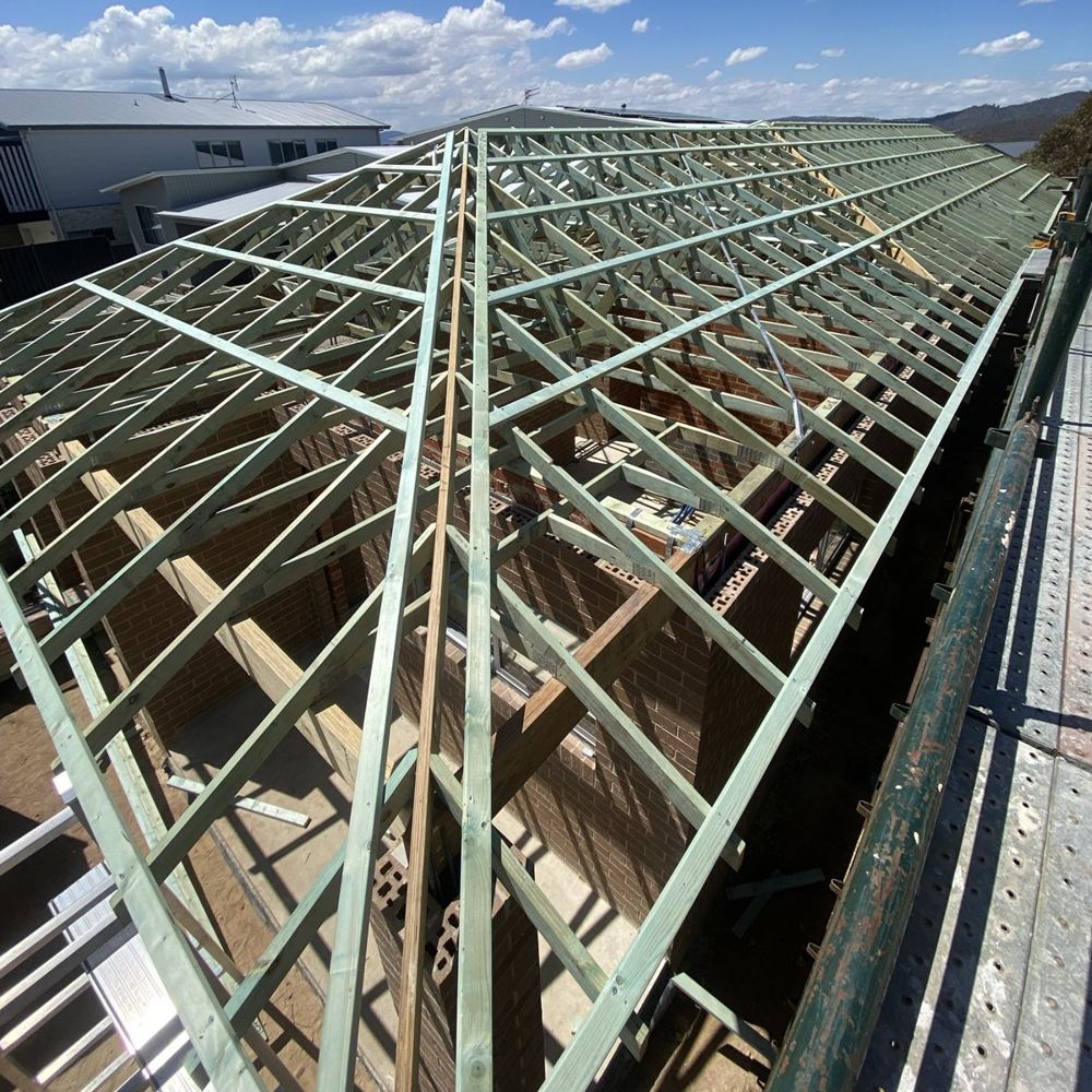 Timber roof trusses on a new brick home with scaffolding