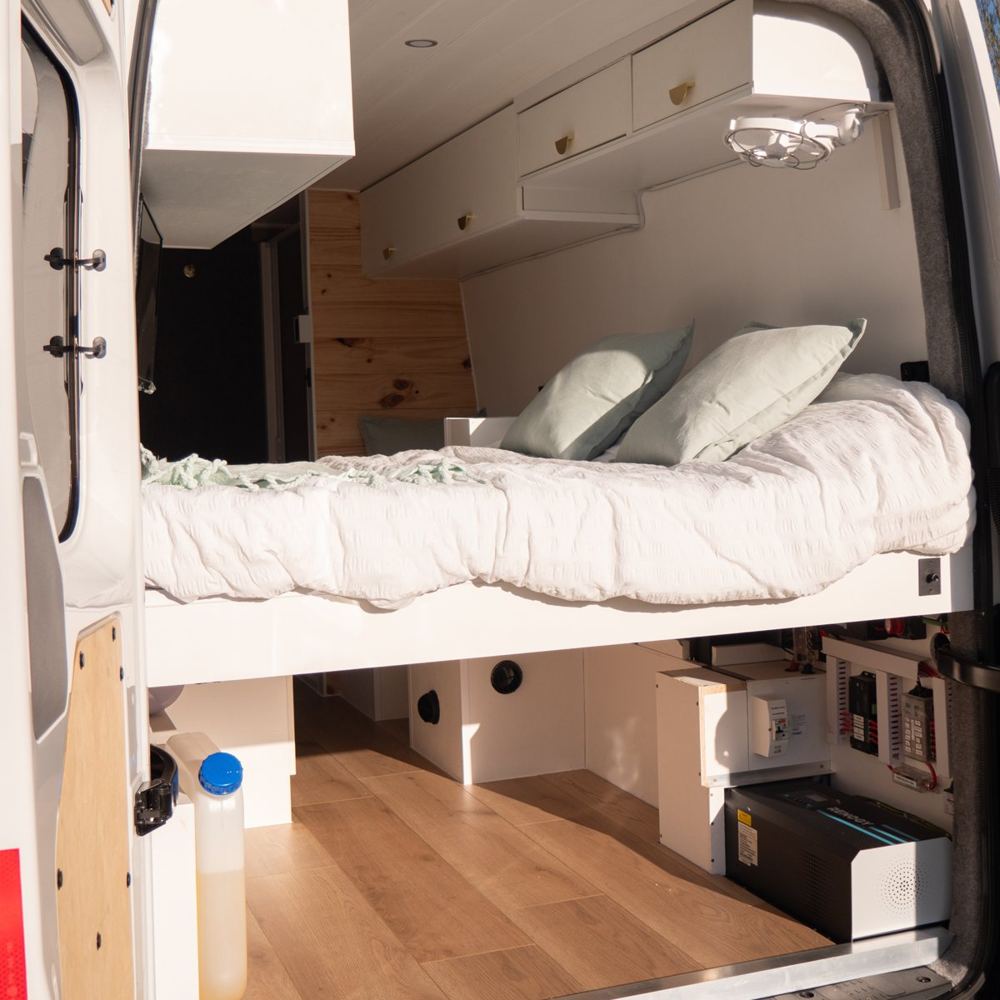 Van conversion interior with bed, overhead storage and timber floor